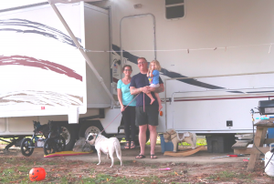 rv family in front of vehicle with girl and dog